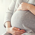 Femme enceinte tenant son ventre - Grossesse facteur influençant la taille des seins d'une femme - Comment se développent les seins - ShytoBuy France