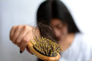 Femme tenant un peigne avec les cheveux perdus