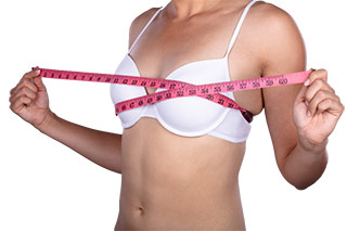 Femme mesurant sa poitrine avec un mètre de couture pour voir si elle a grossi - Fenugrec : l'ingrédient idéal pour une poitrine plus grosse