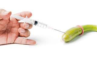 Injection du seringue dans un concombre pour symboliser les injections d'acide hyaluronique dans la pénis Injection du seringue dans un concombre pour symboliser les injections d'acide hyaluronique dans la pénis