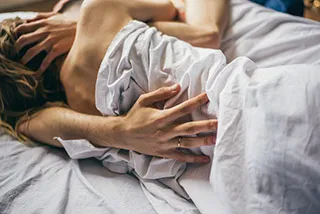 Couple dans un lit sous des draps représentant la rubrique le molluscum est-il sexuellement transmissible | Shytobuy.fr
