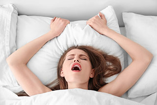 Femme dans son lit en train de vivre un orgasme intense - Comment satisfaire les femmes au lit