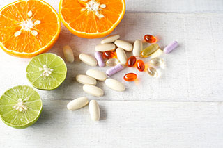 Gélules de vitamines et autres compléments alimentaires à côtée d'une orange et d'un citron vert coupés en deux - Comment soulager les symptômes de la ménopause ? - ShytoBuy France
