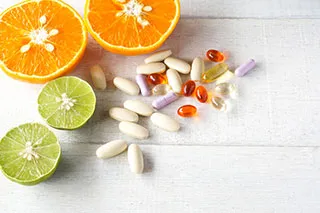 Gélules de vitamines et autres compléments alimentaires à côtée d'une orange et d'un citron vert coupés en deux - Comment soulager les symptômes de la ménopause ? - ShytoBuy France